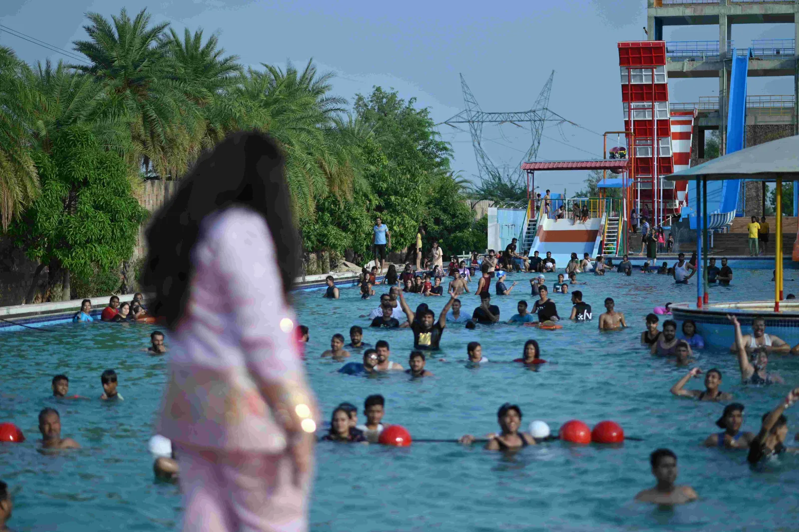 Guests swimming in the wave pool with the water slide tower behind, Shagun Resorts Jodhpur